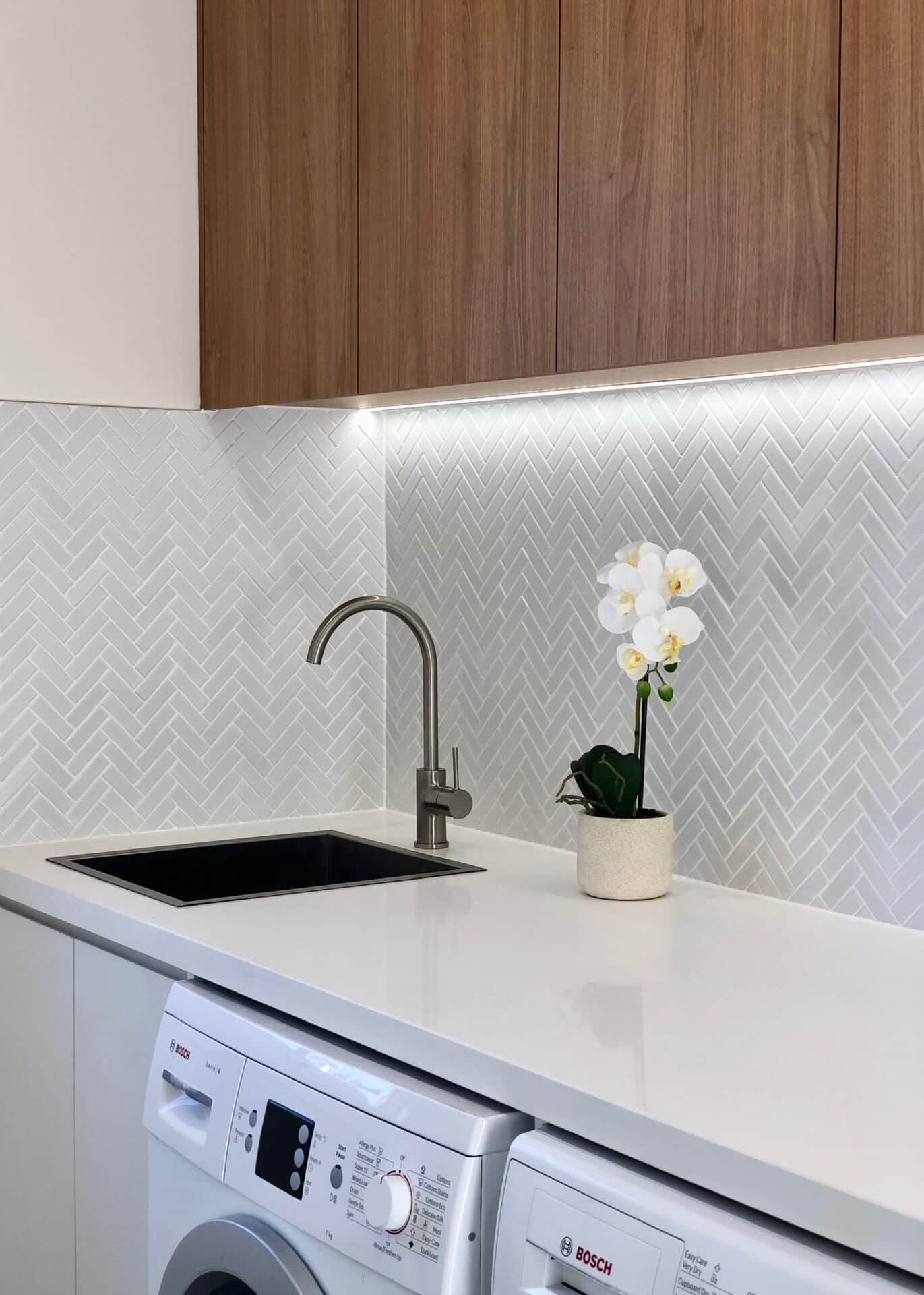 a white kitchen counter with a sink and a plant