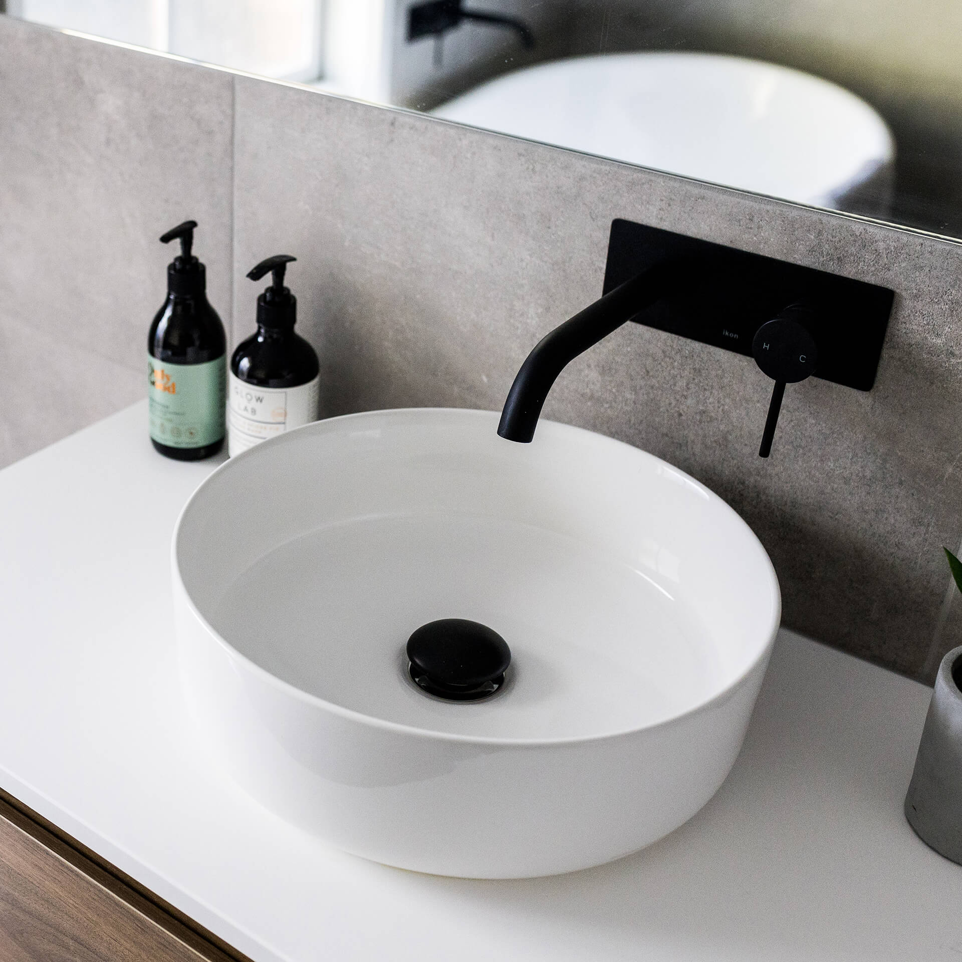 a sink with a wooden vanity and a black faucet
