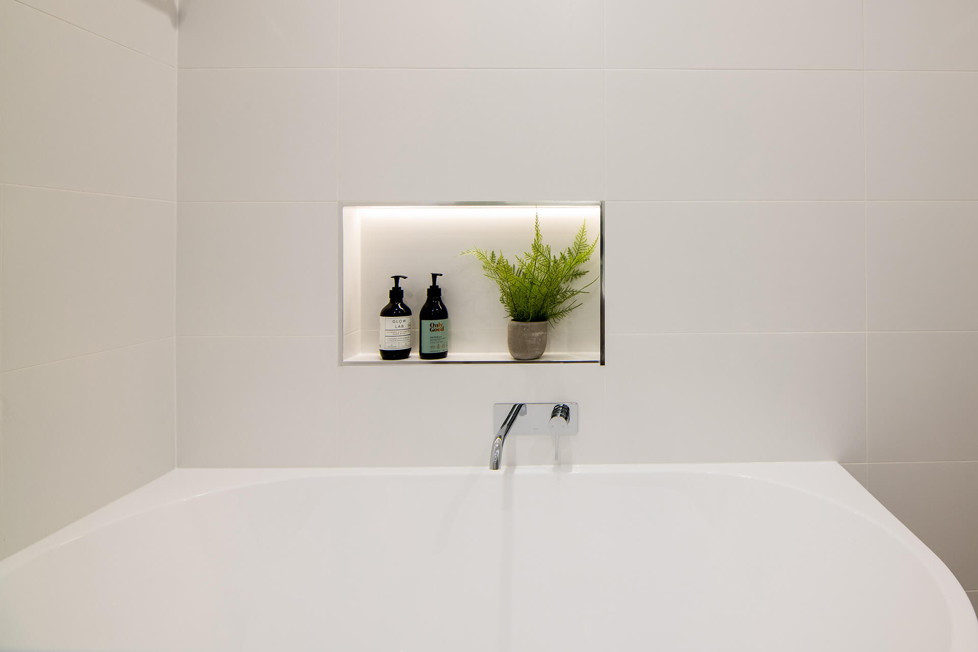 a bathtub with a shelf with a plant in it