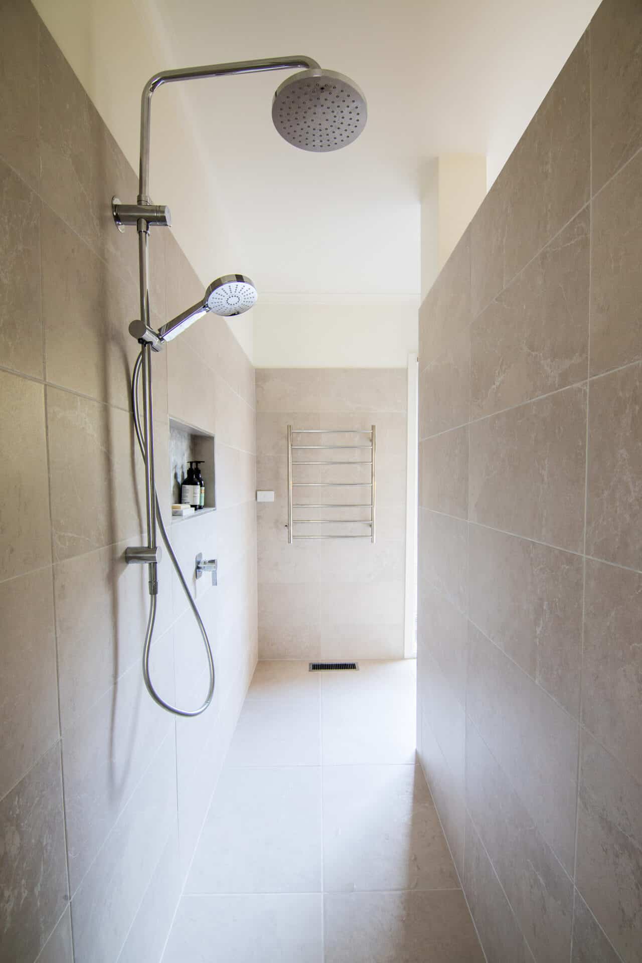 a clean shower with a shower head and rails