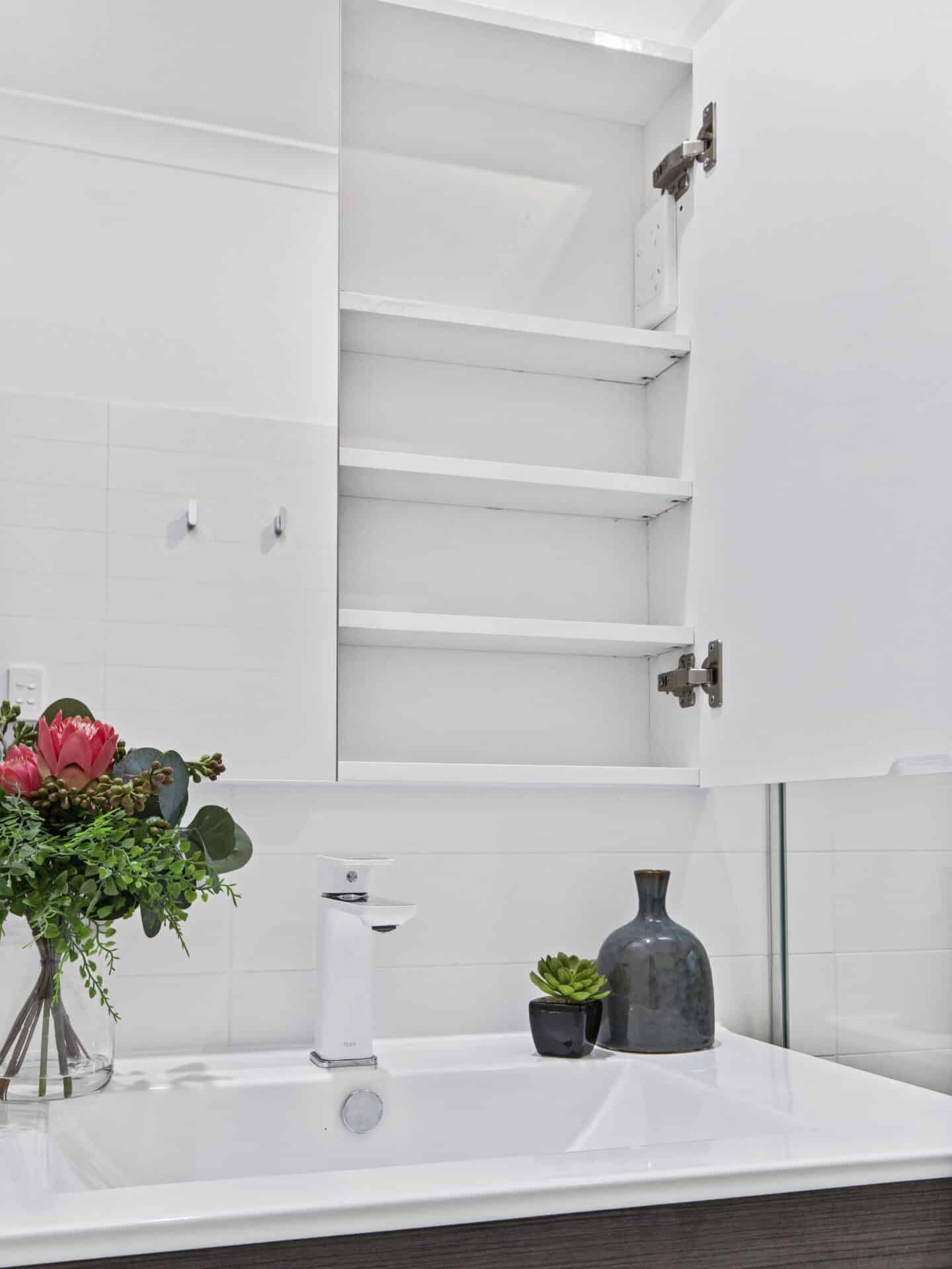a white bathroom with a vase of flowers and a sink