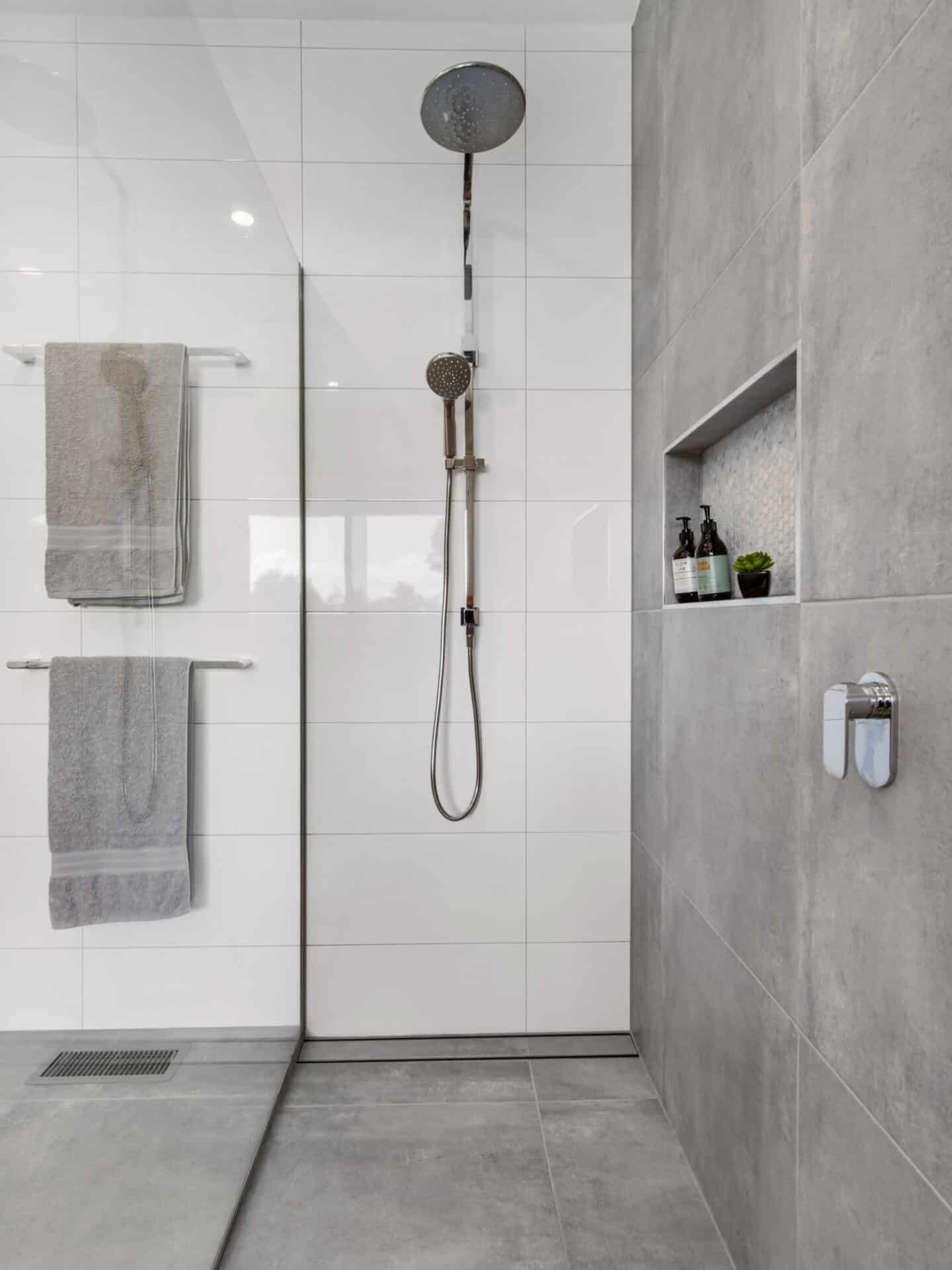 a shower with a shower head and a towel on the wall