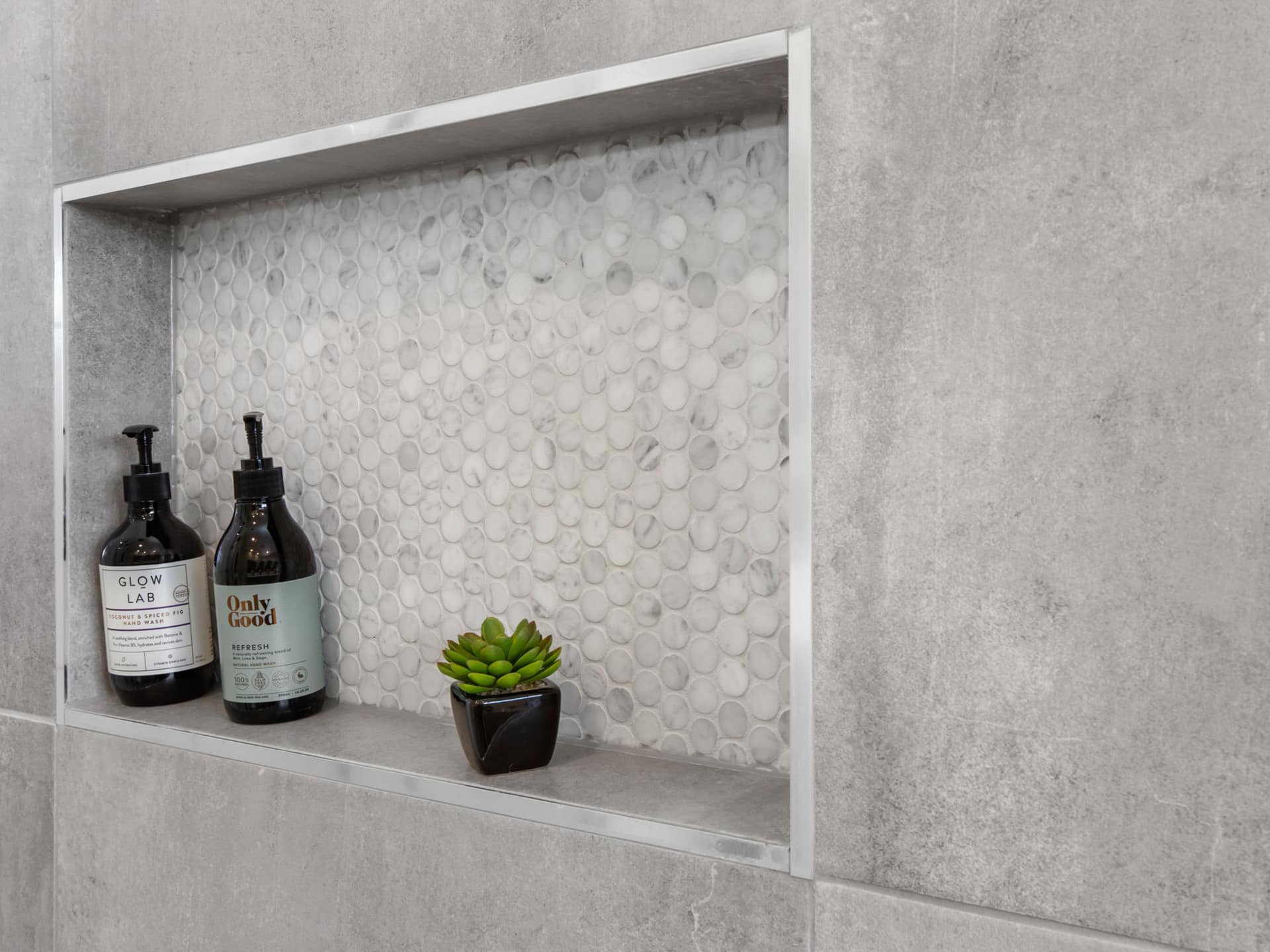 a shower shelf with bottles and a plant on it