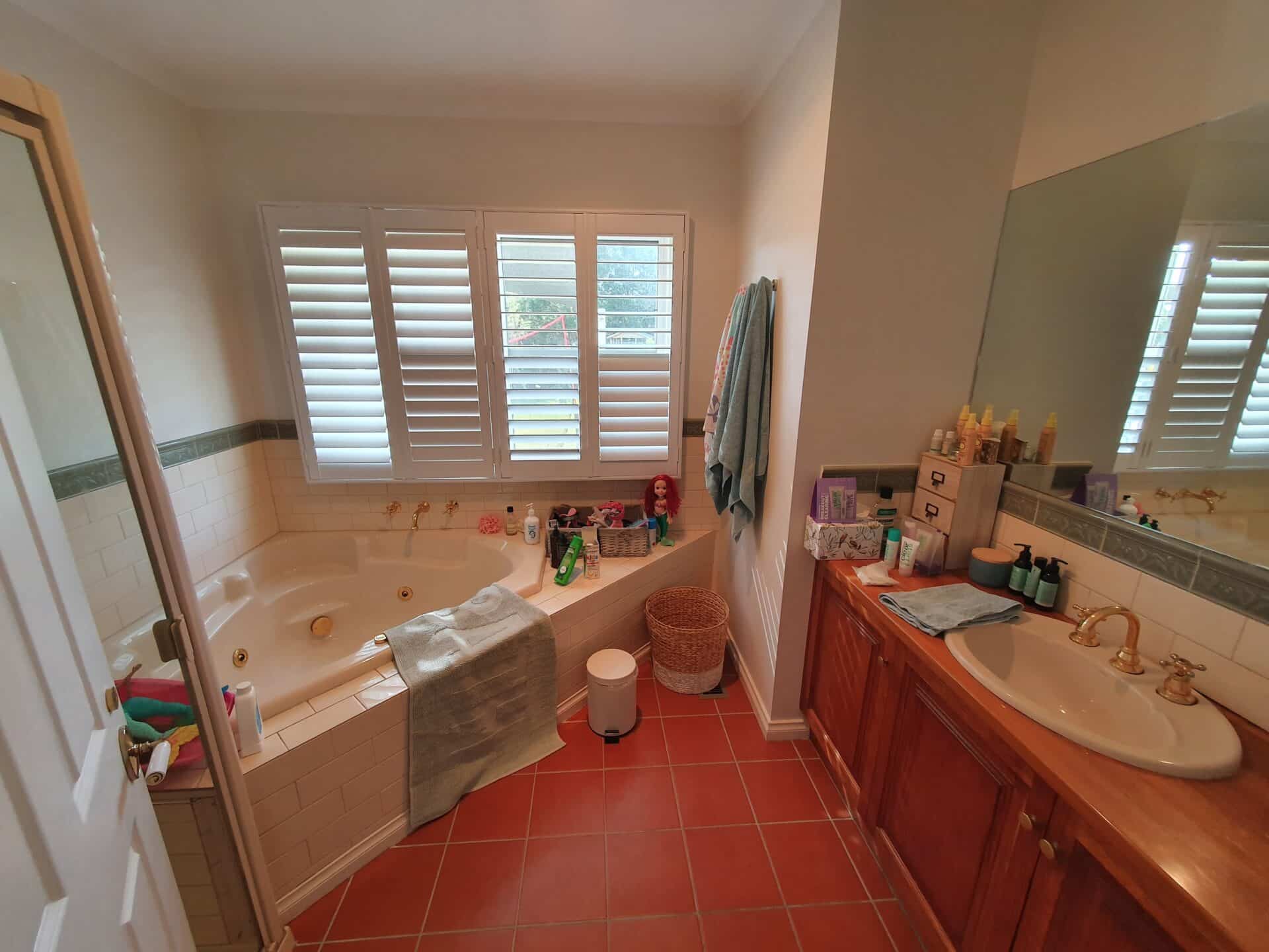a bathroom with a tub and sink and a red floor tiles