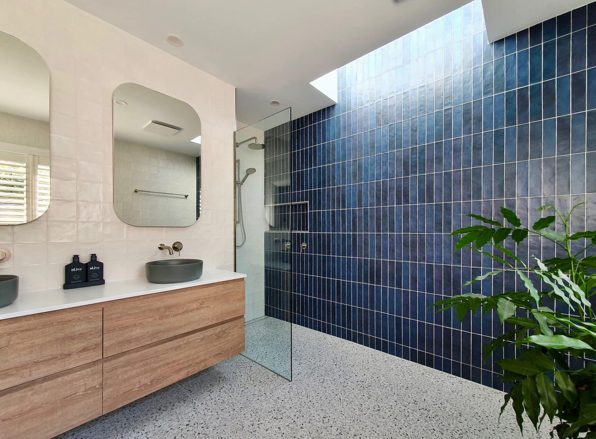 a bathroom with a sink and a shower and blue wall tiles