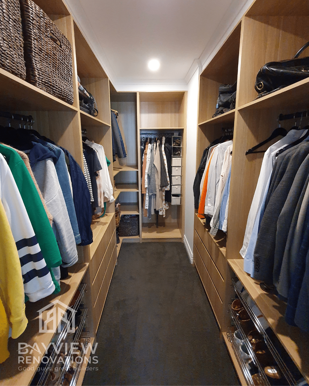 a walk in closet with clothes on the shelves