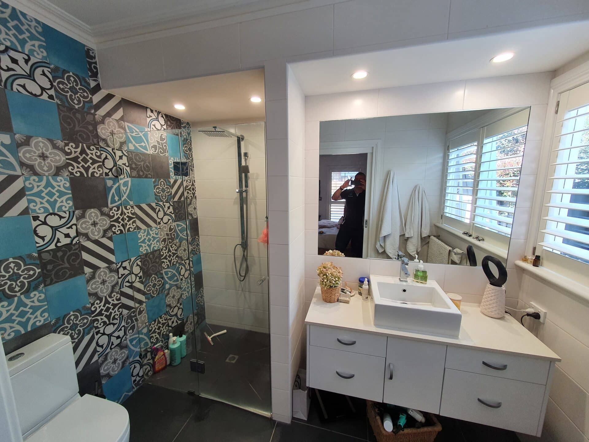 a bathroom with a mirror and a sink with patterned wall tiles