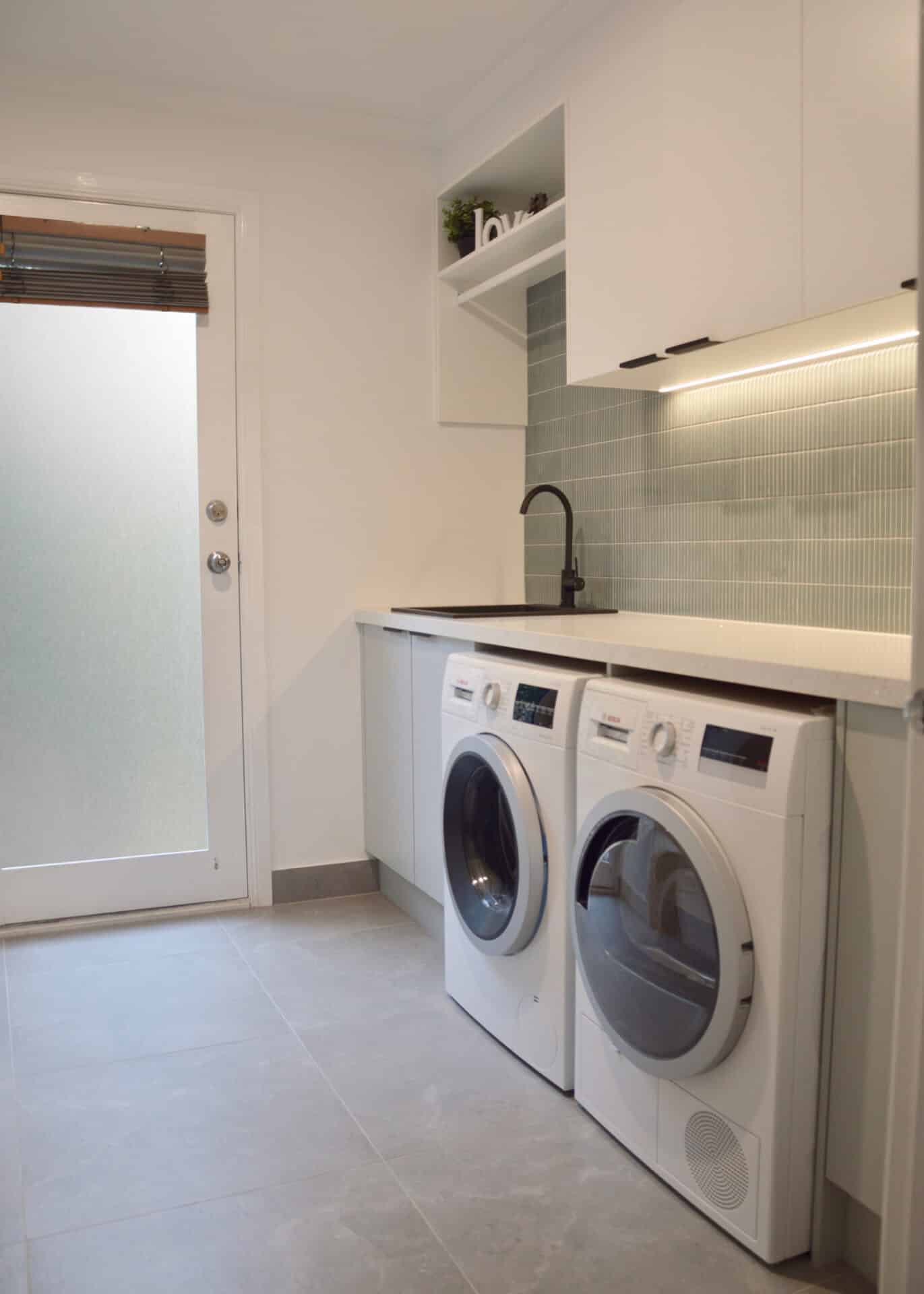 a laundry room with washer and dryer under a sink