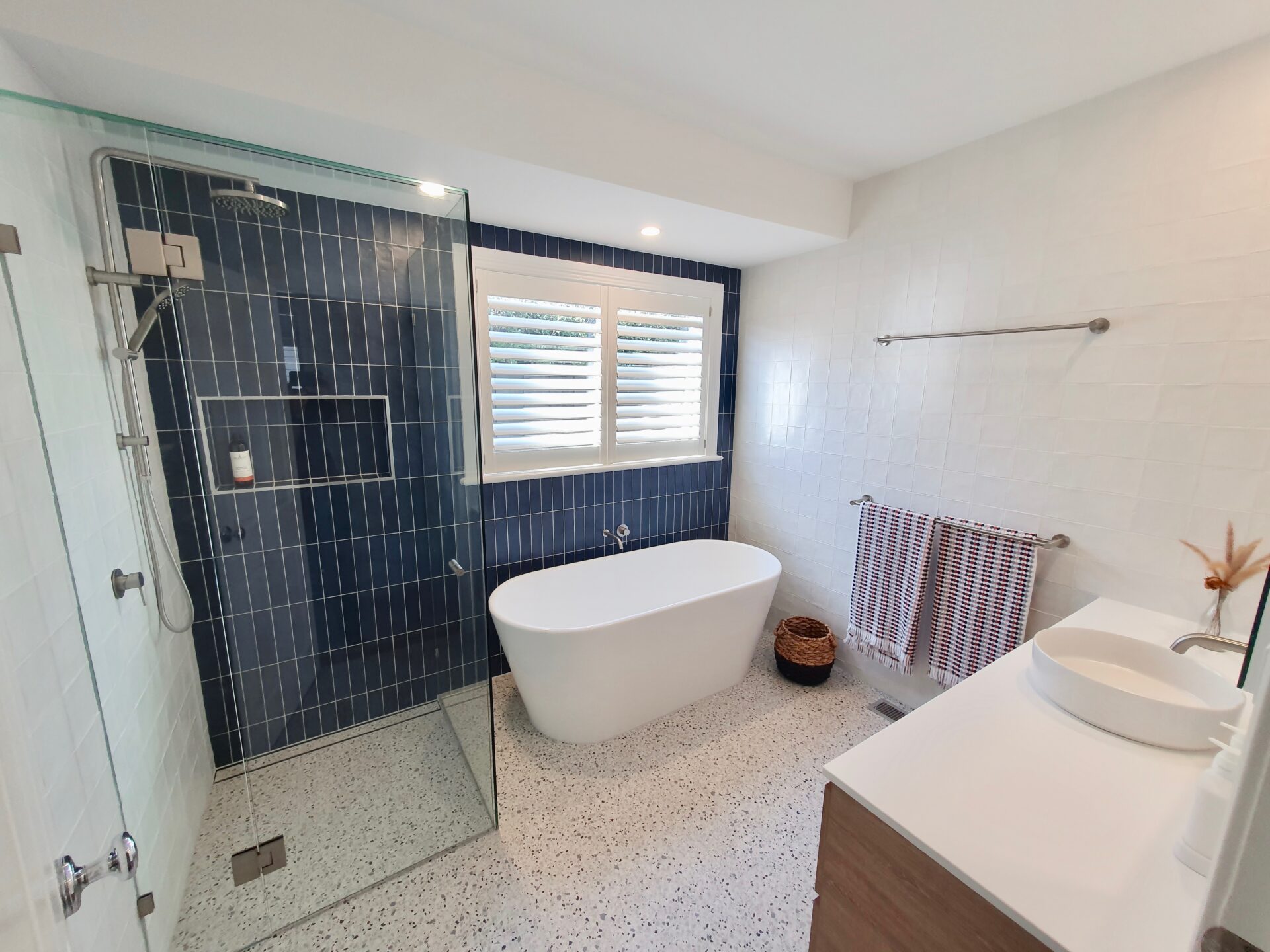bathroom with a sink, bath tub, and a shower with blue wall tiles