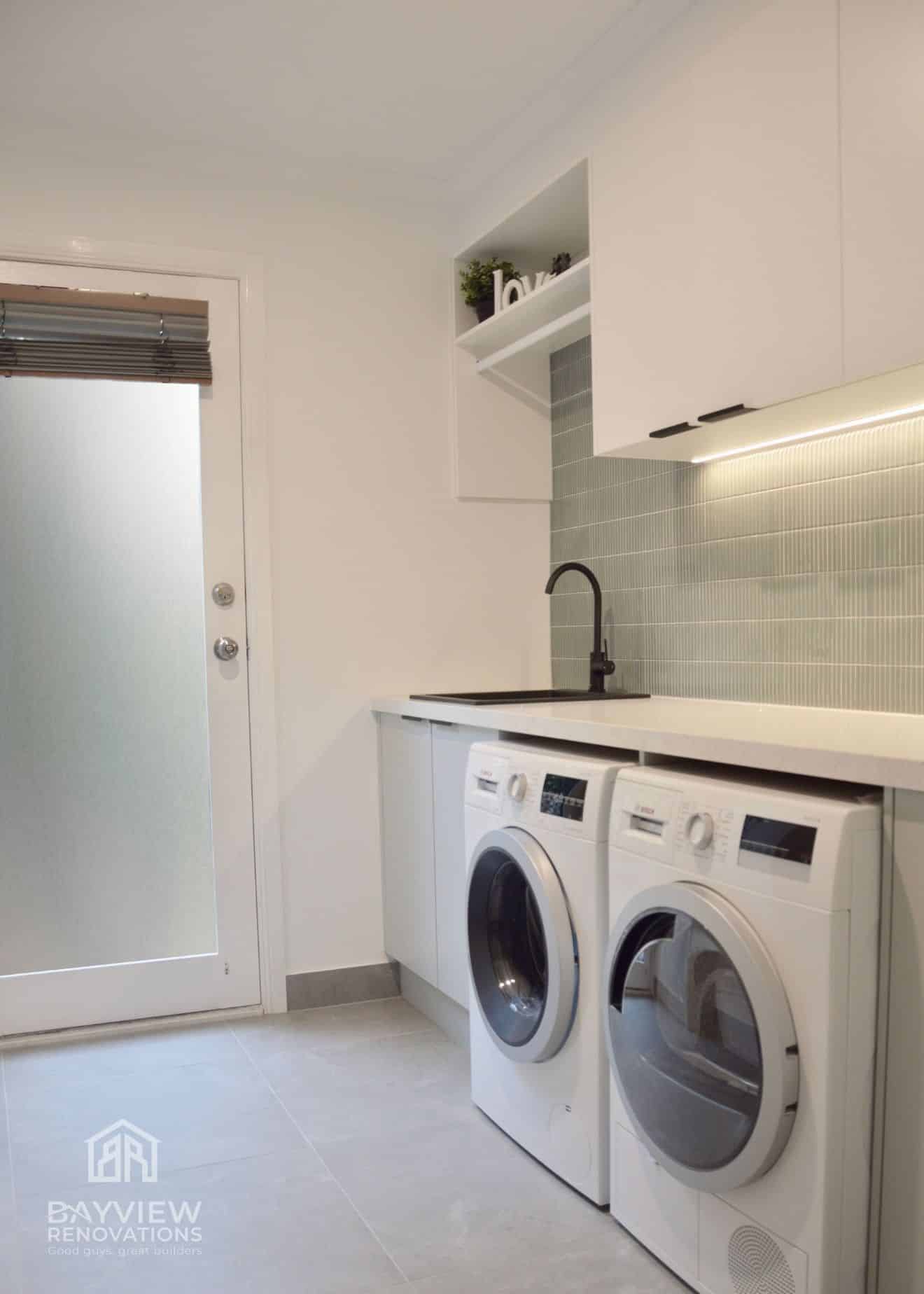 a laundry room with white cabinets and washing machines