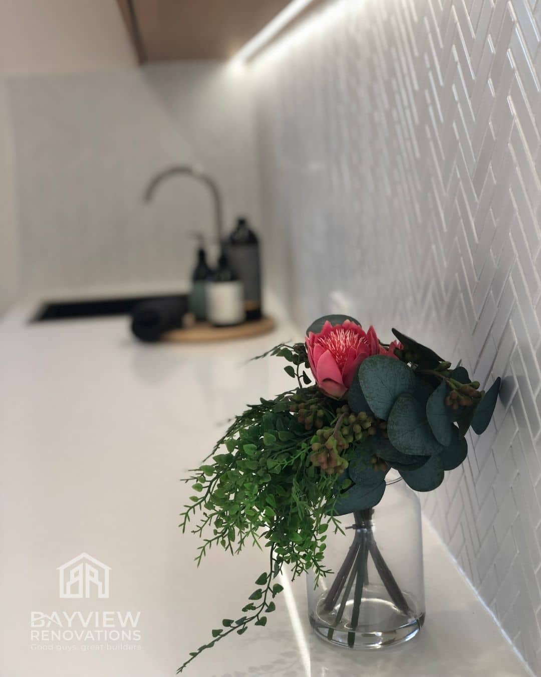 a vase with flowers in it in front of a sink