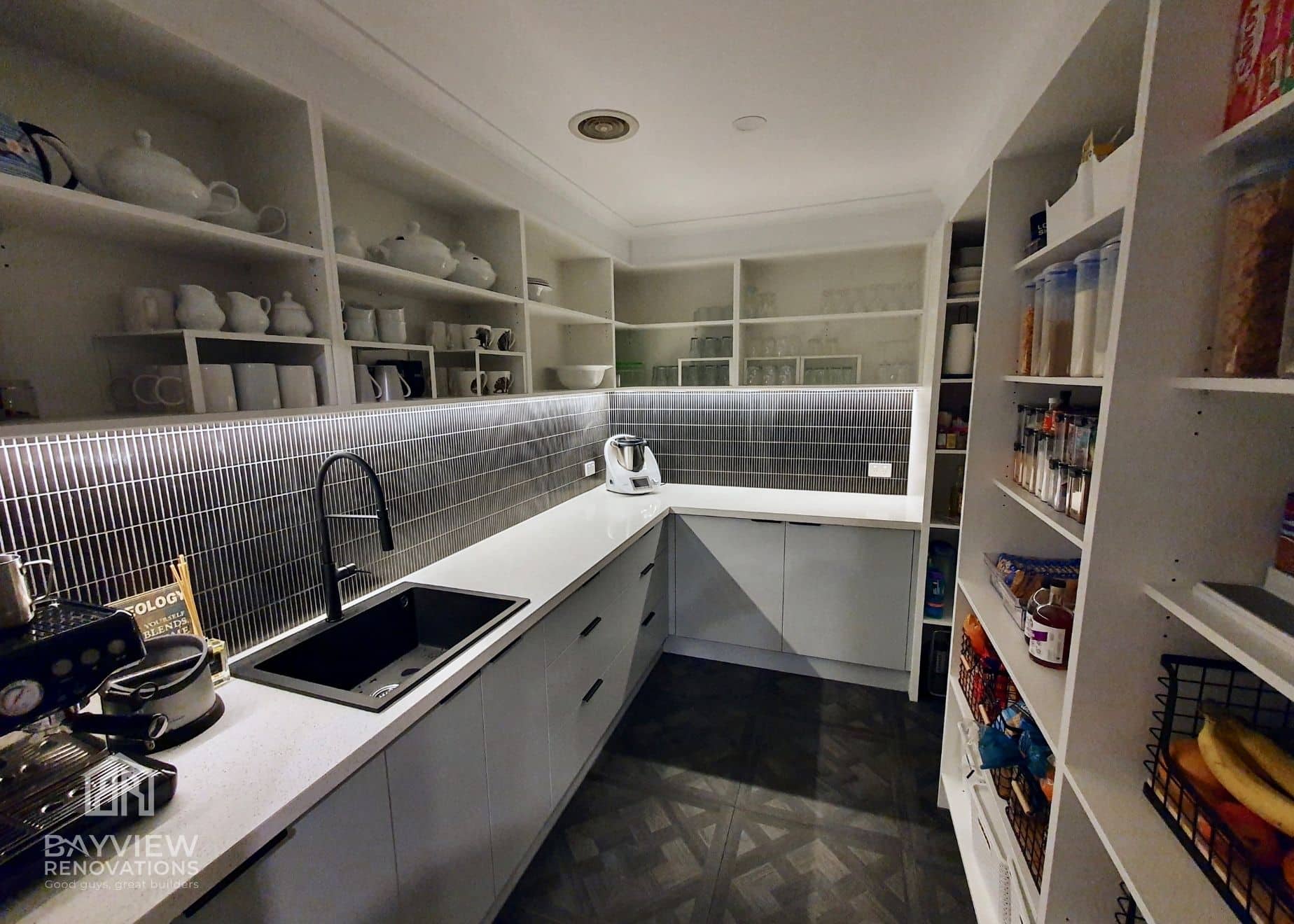 a kitchen with white cabinets and shelves