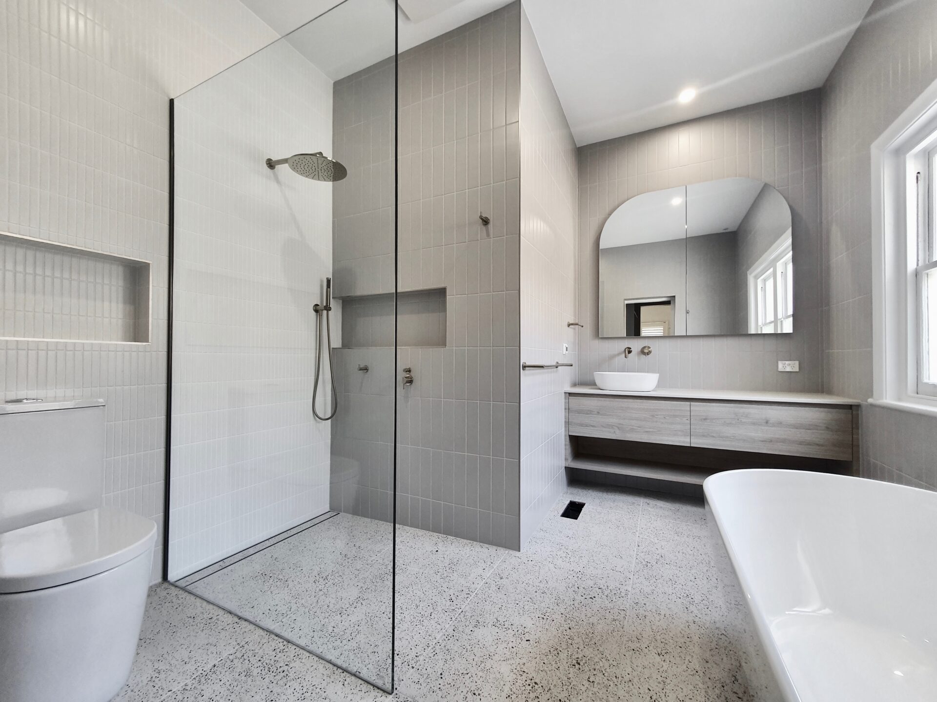 modern bathroom with a toilet, shower area, and a bath tub