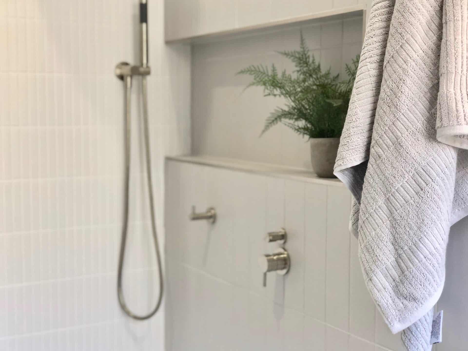 close up view of a modern bathroom with gray wall tiles, shower area and a towel hanging at the wall