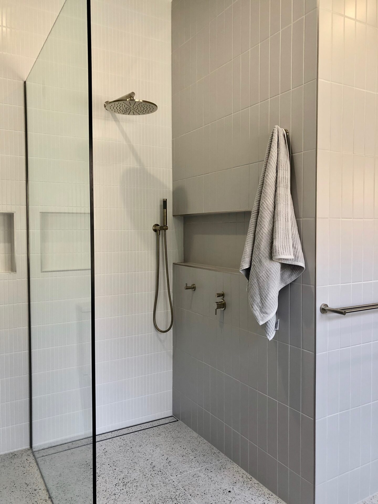 modern bathroom with gray wall tiles, shower area and a towel hanging at the wall
