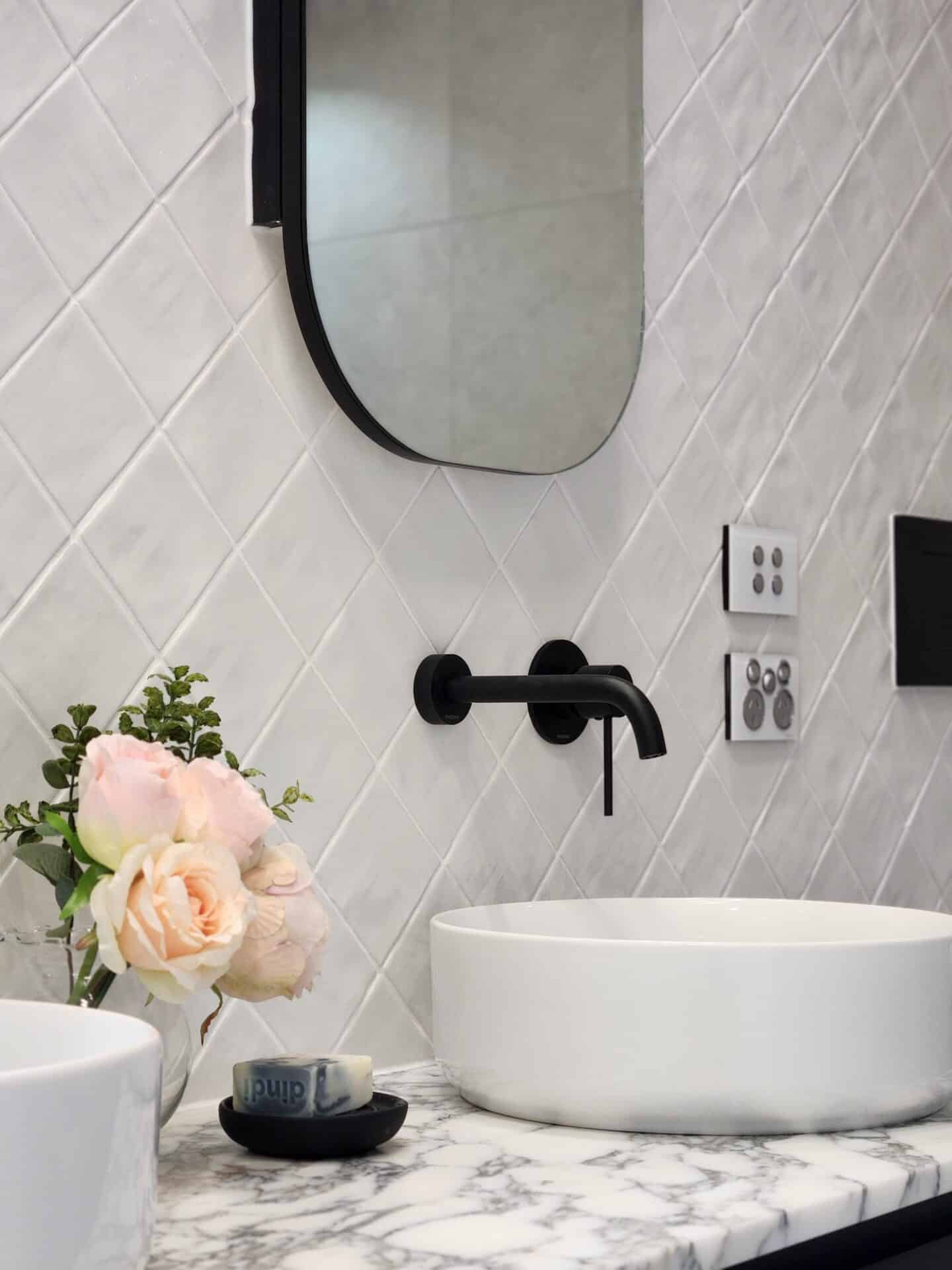 White ensuite with a sink, a flower vase and a soap.