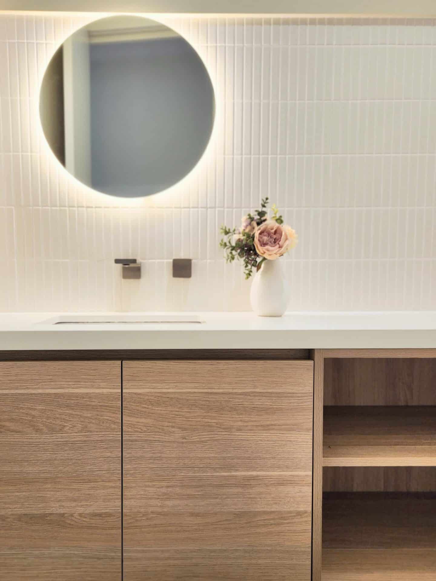 A bathroom vanity with a round mirror above it.
