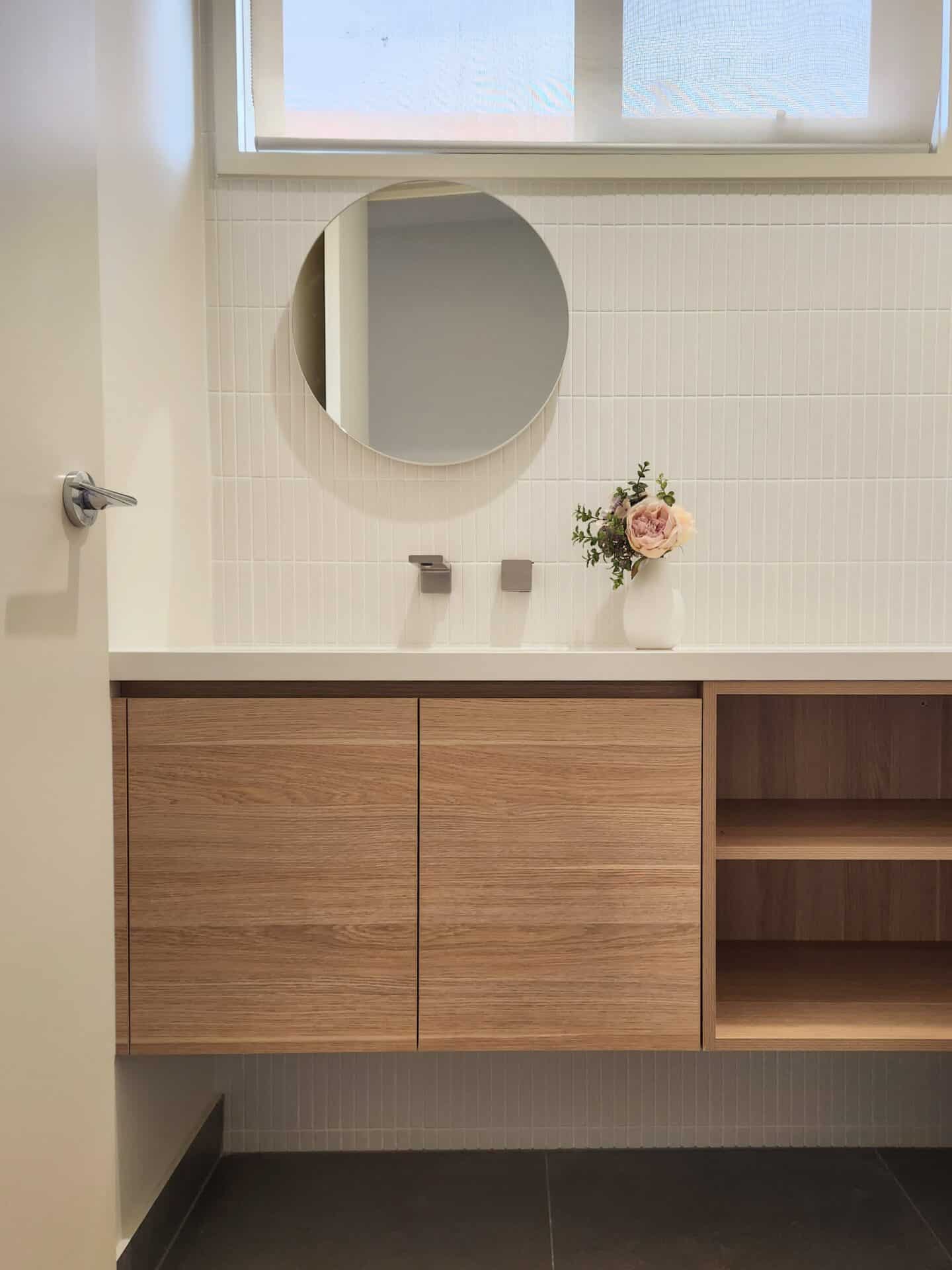 A powder room with a sink, a mirror and wood cabinets.