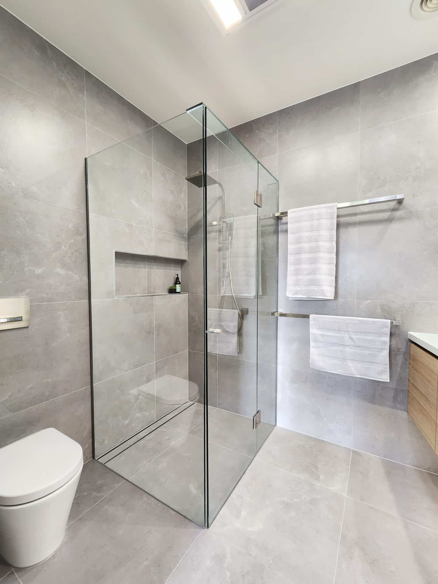 A modern bathroom with a glass shower door and a toilet.