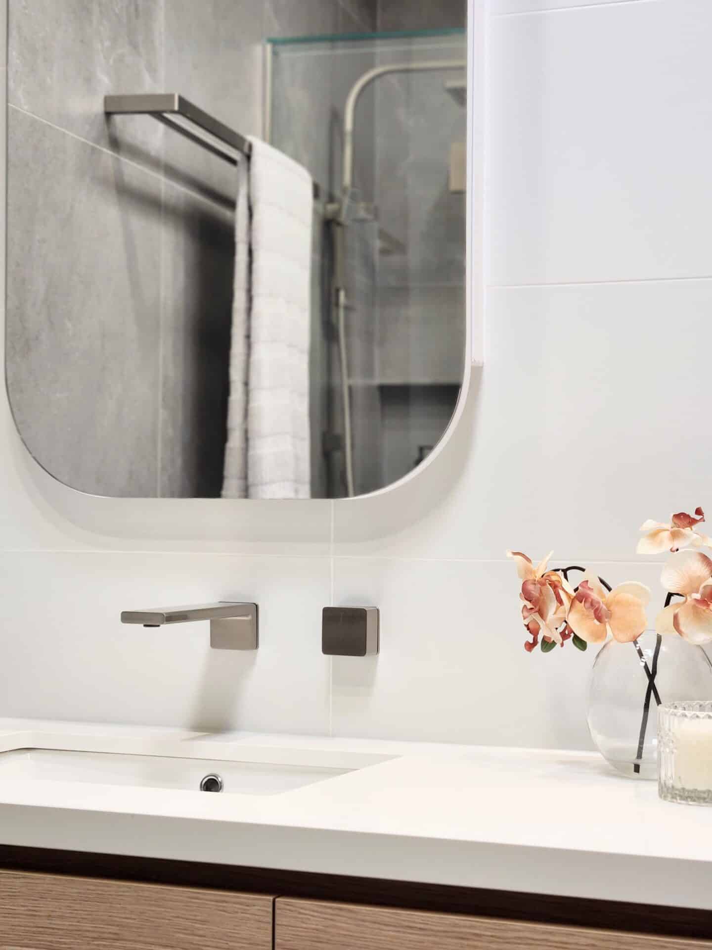 A bathroom sink with a vase of flowers on it.