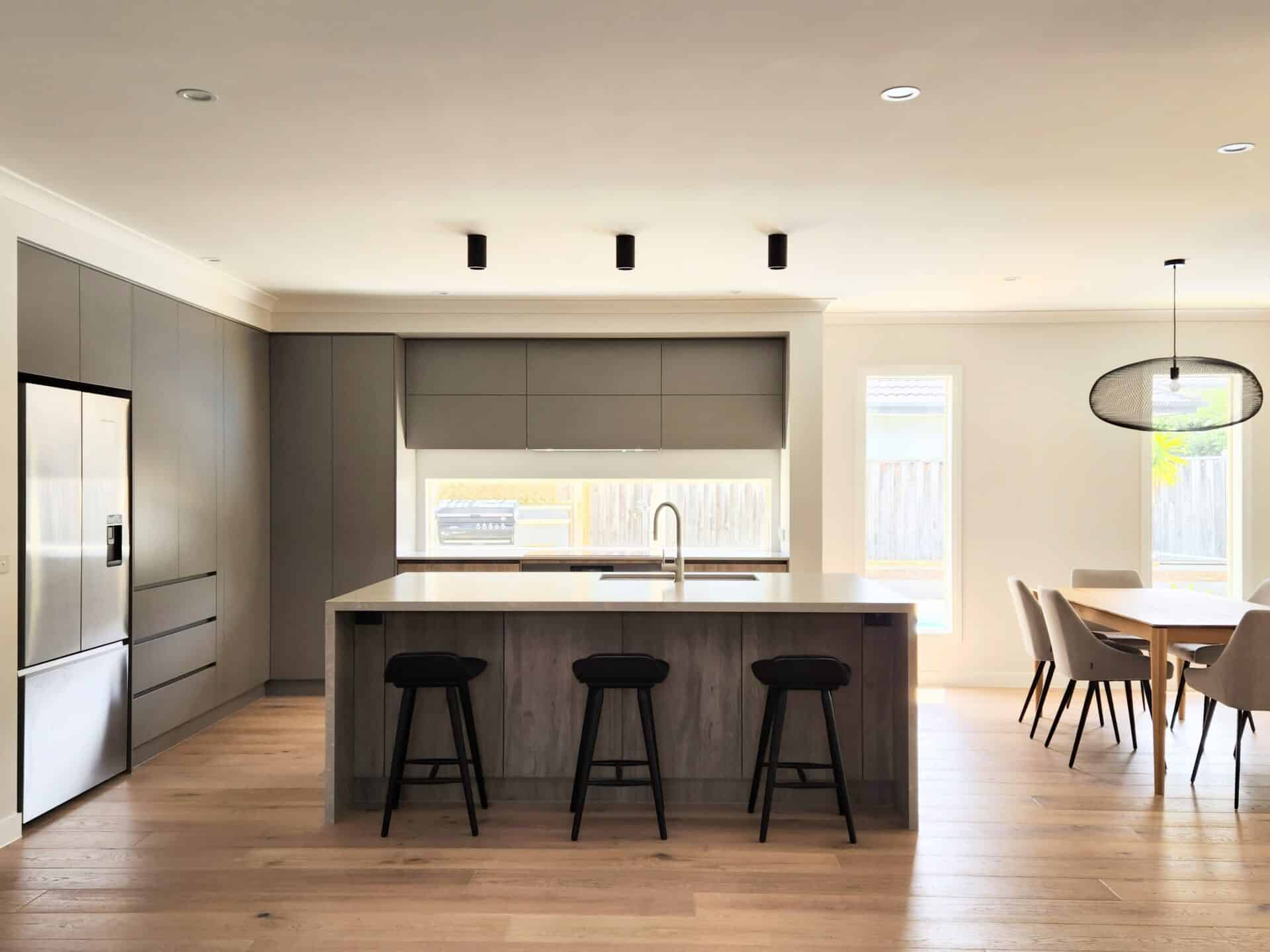 a modern kitchen and dining area with wooden flooring, stools and furniture.