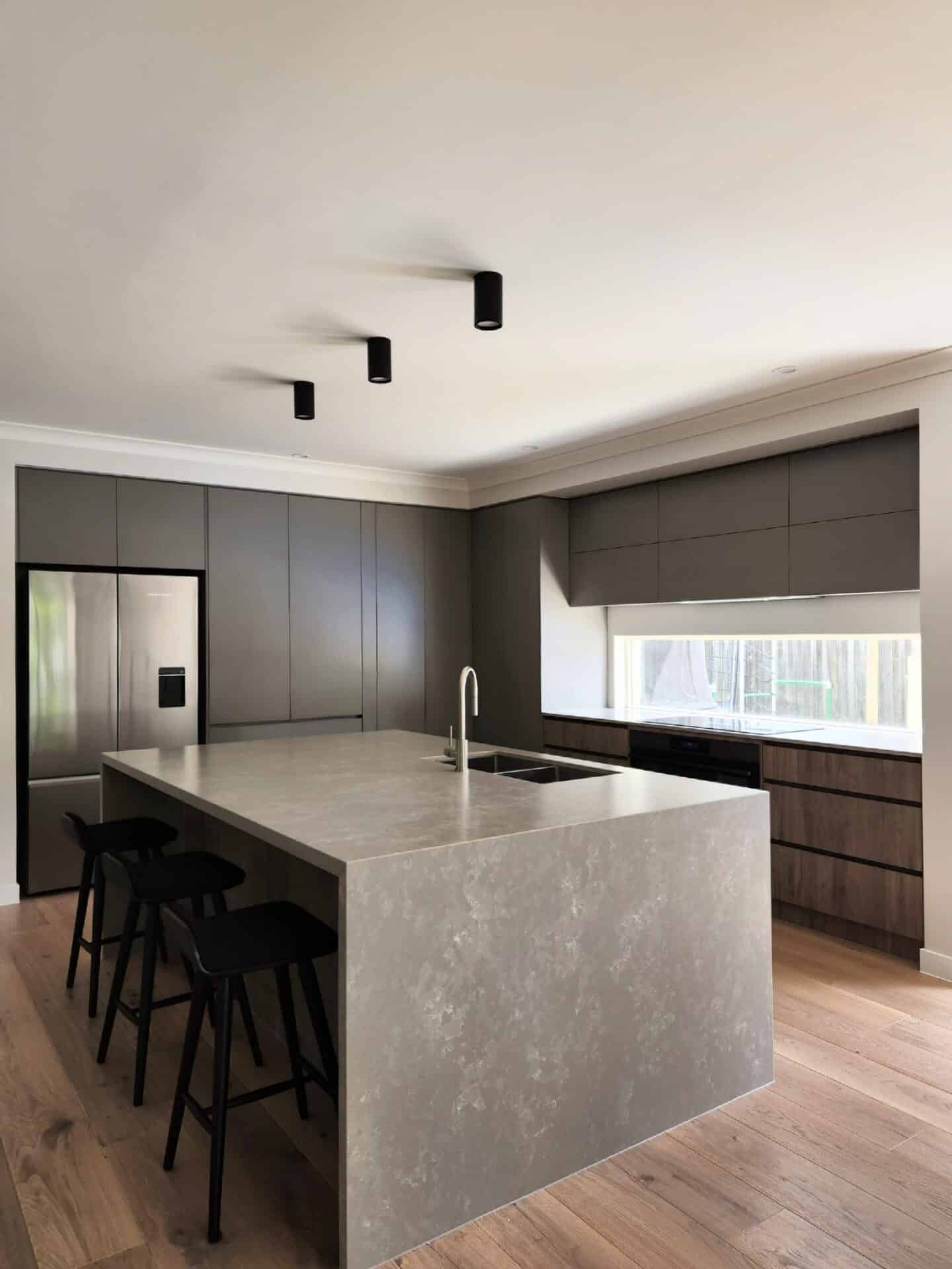 modern kitchen with a gray counter, sink and high stools.