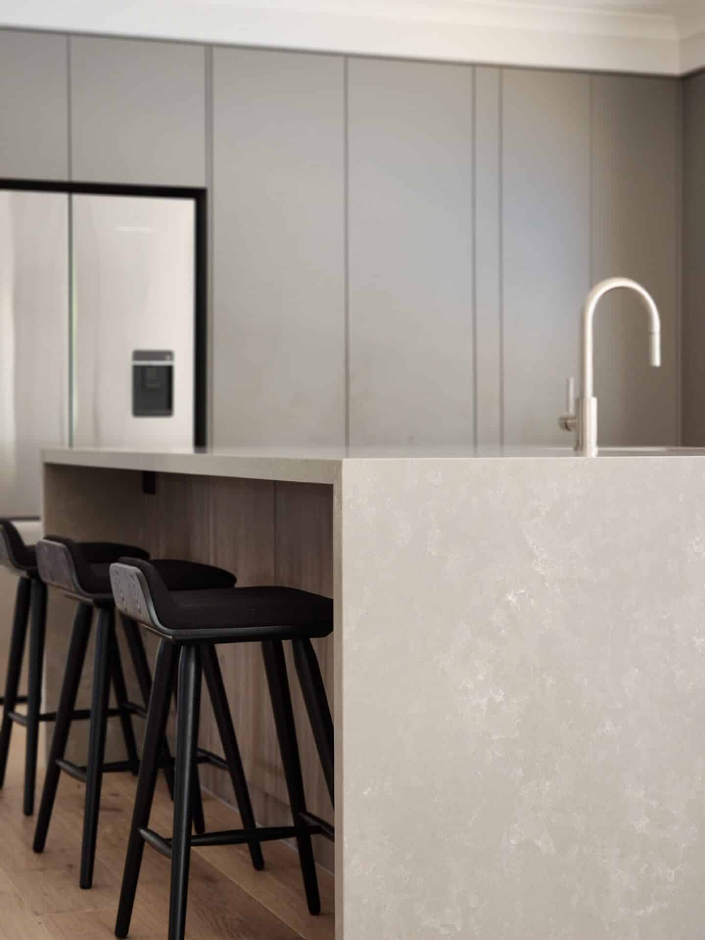 a modern kitchen with sink in the counter ang high stools.