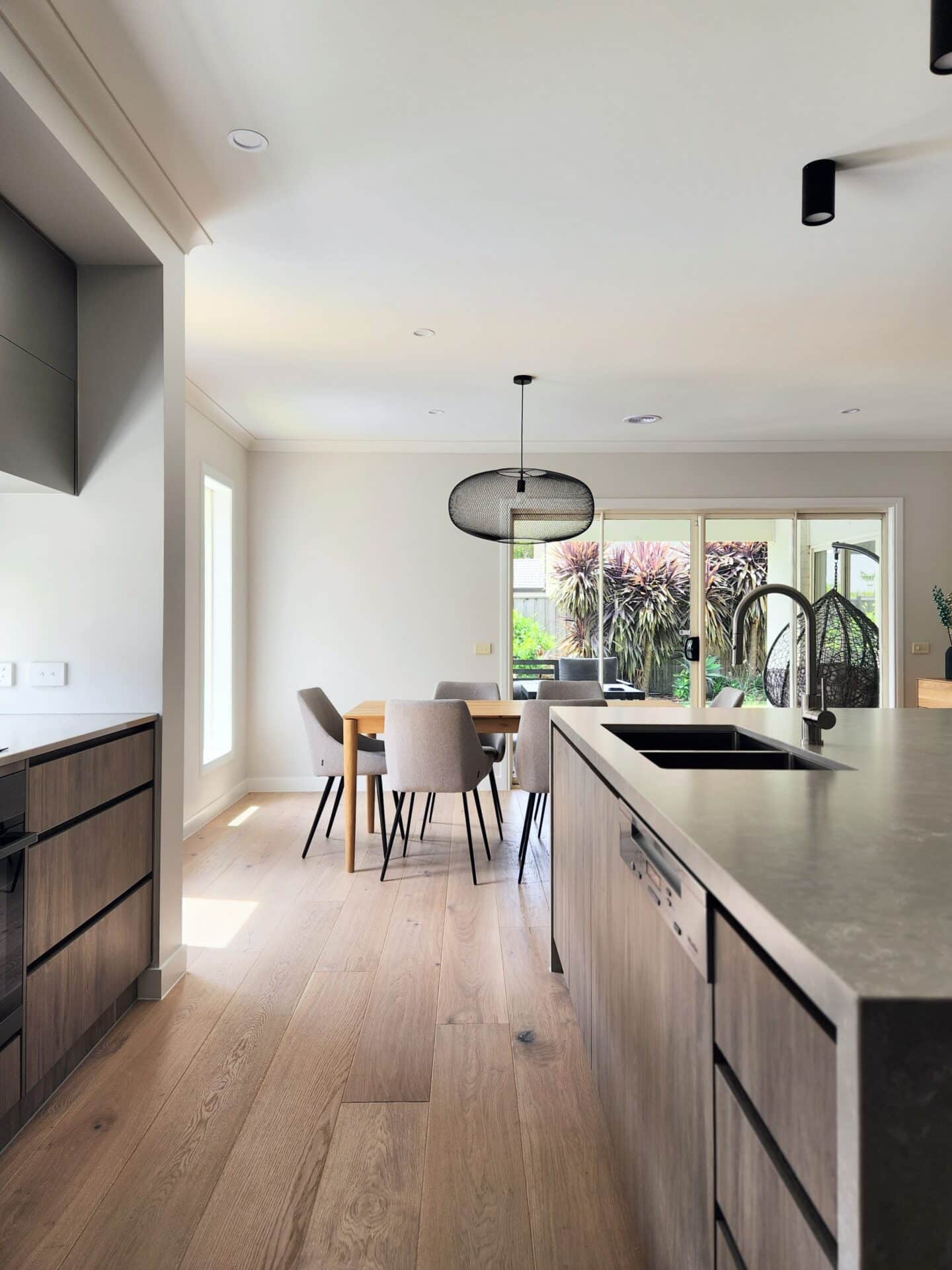 a modern kitchen and dining room with wood flooring, cabinets and quality furniture.