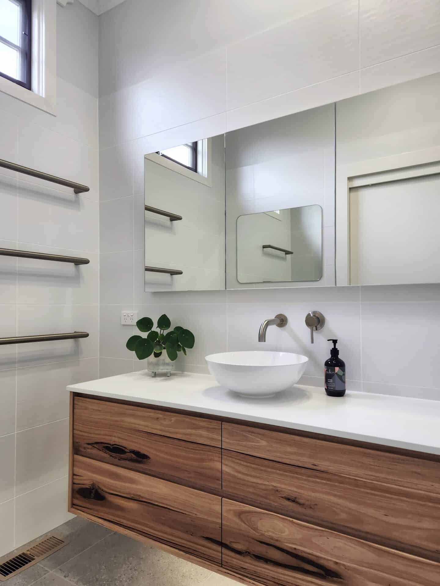 a modern white ensuite with wooden cabinets and vanity.