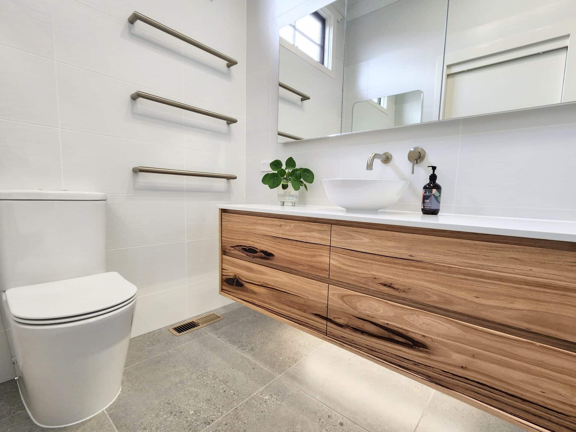 a white modern bathroom with gray floor tiles, white sink, and a wood cabinet.