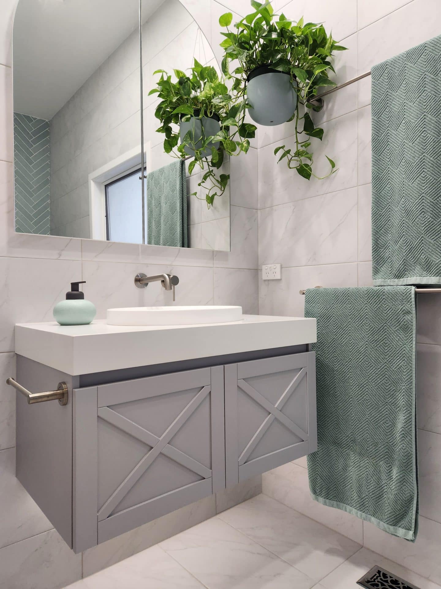 a renovated ensuite bathroom with a sink, mirror, and green plant.