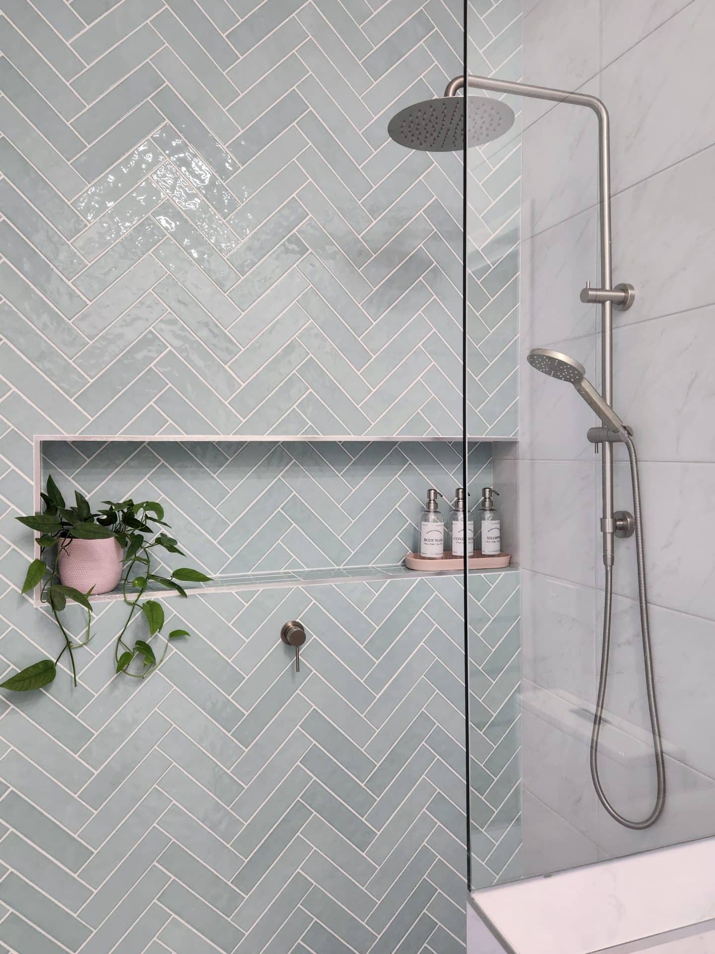 a bathroom with blue herringbone tiles and a glass shower.