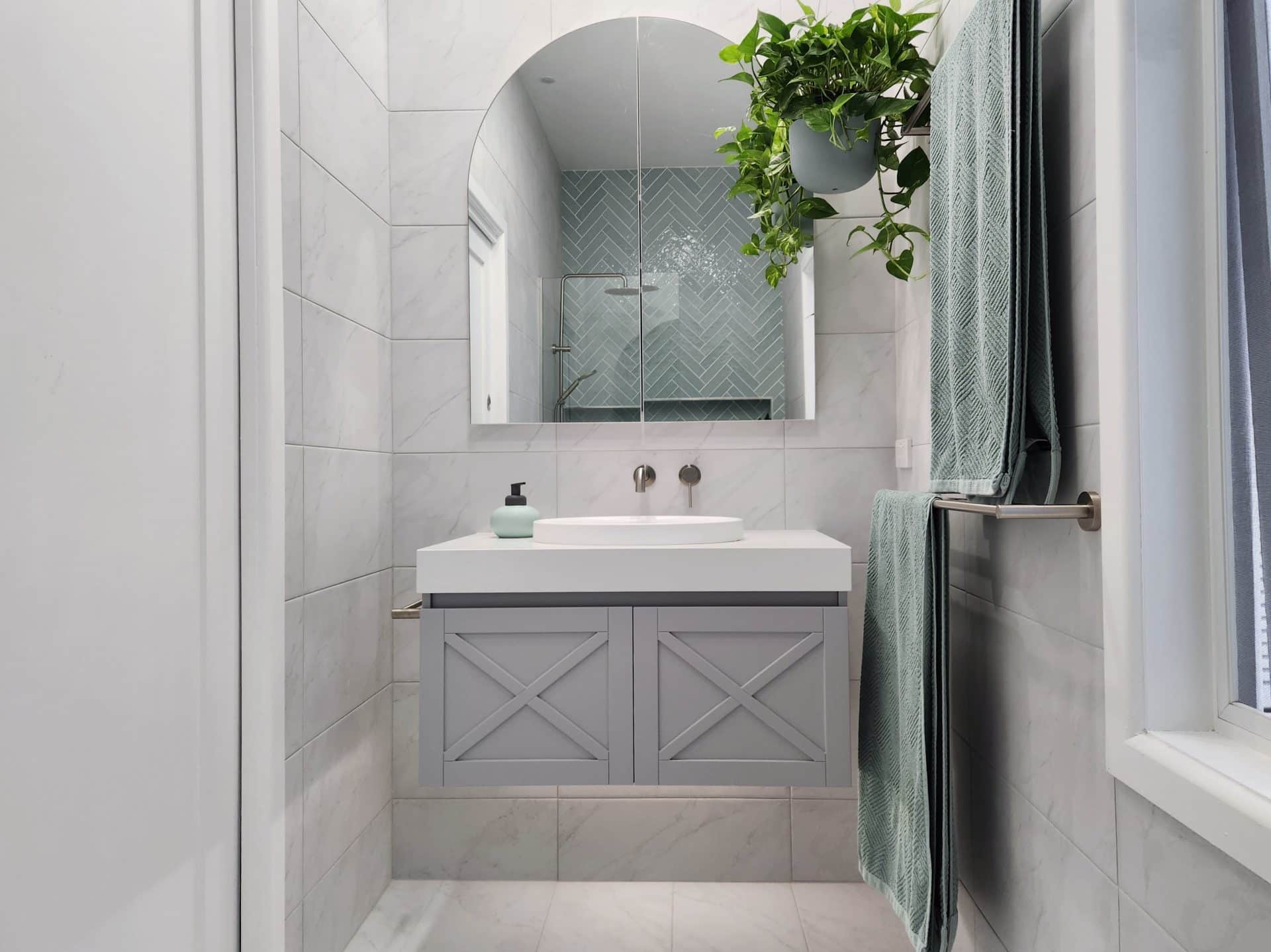 a small bathroom with a grey tiled floor and a plant on the wall.