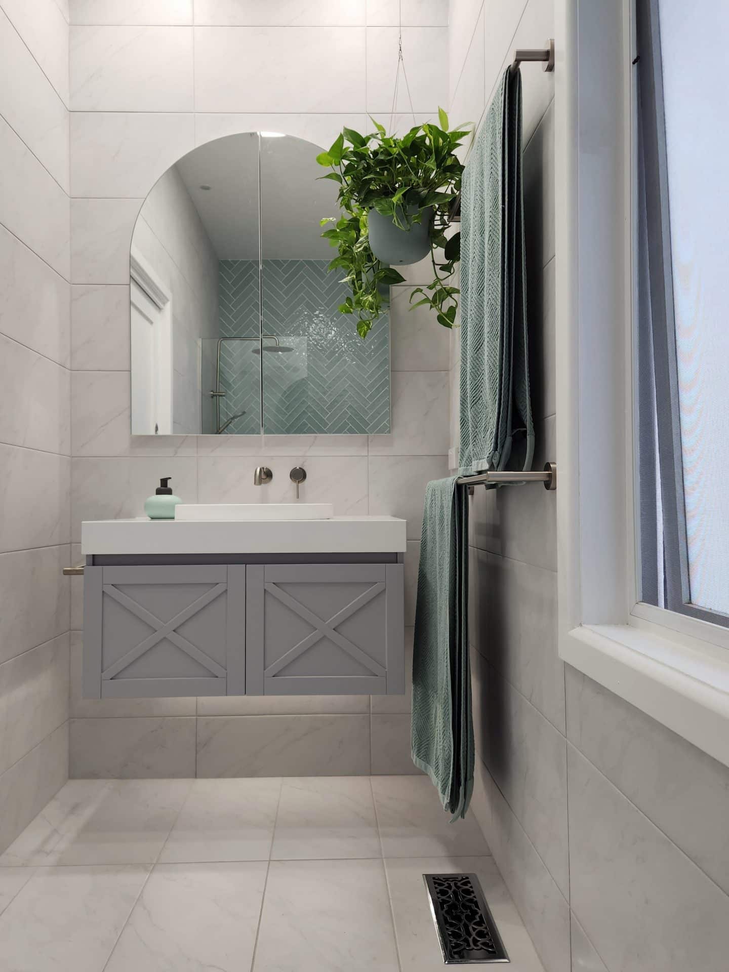 a modern bathroom with grey tiles and a plant on the wall.